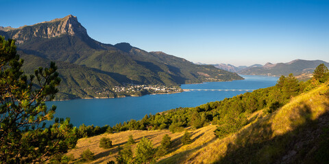 The village of Savines-le-Lac with its bridge and the Grand-Morgon mountain peak in Summer along the Serre-Poncon lake. Durance Valley, Hautes-Alpes, Ecrins National Park, European Alps, France