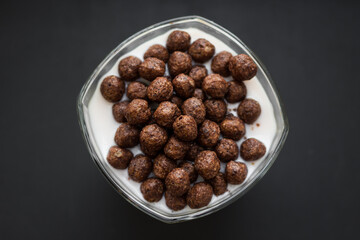 Children food. Delicious light breakfast. Crispy chocolate balls. Flakes with yogurt. Healthy food. A nutritious snack. Food photo. Sweet milk dessert. Morning diet. Cereals, cocoa and milk.