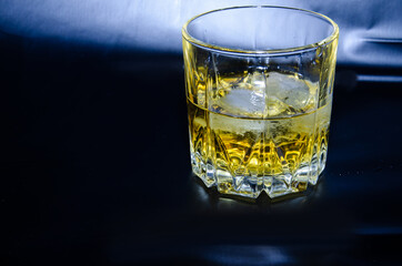 A glass of whiskey with ice on a black background. Copy the space.