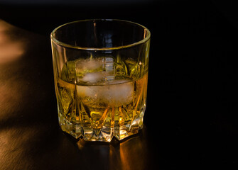 A glass of whiskey with ice on a black background. Copy the space.