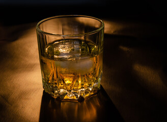 A glass of whiskey with ice on a black background. Copy the space.