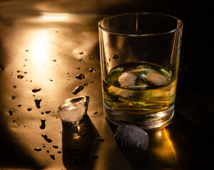 A glass of whiskey with ice on a black background. Copy the space.