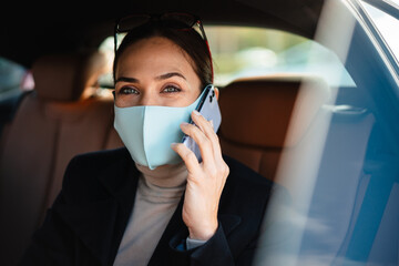 Business woman sitting in a car in face mask