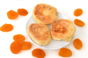 Delicious cheesecakes and dried apricots for breakfast on white background