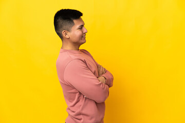 Young Ecuadorian man isolated on yellow background in lateral position