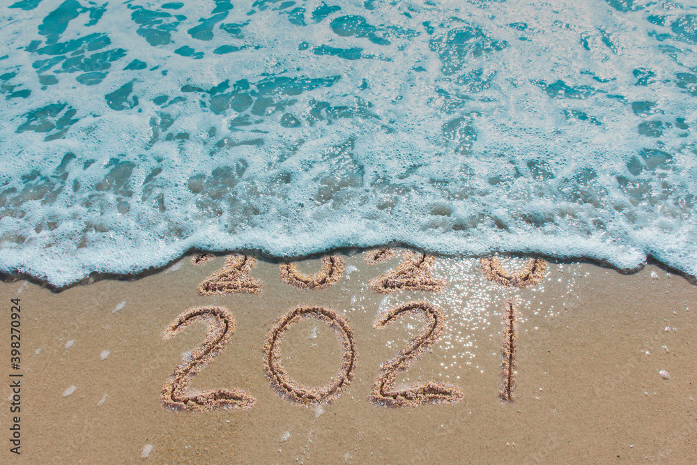 Wall mural message year 2020 replaced by 2021 written on beach sand background. good bye 2020 hello to 2021 hap