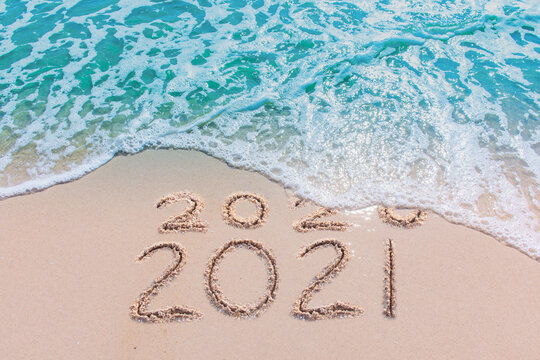 Message Year 2020 replaced by 2021 written on beach sand background. Good bye 2020 hello to 2021 happy New Year coming concept

