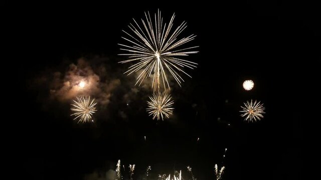 best 4K loop seamless of real shining fireworks long shot 35s for celebration background. golden glowing firework during new year's eve countdown festival in the sky display at night with colorful.