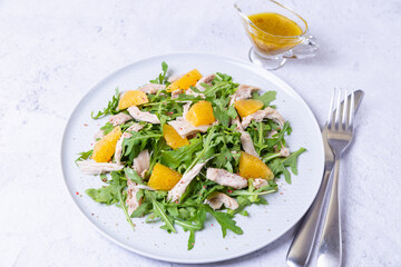 Salad with chicken, oranges and arugula. Dressing with olive oil and grain mustard. Close-up.