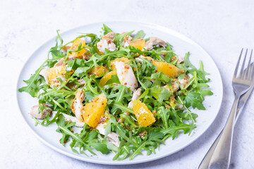 Salad with chicken, oranges and arugula. Dressing with olive oil and grain mustard. Close-up.