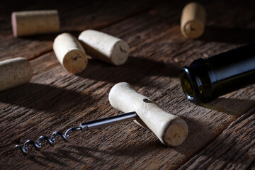 Collection of wine stoppers, bottle and corkscrew on wooden background.