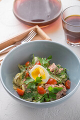 bowl of salad with tuna fish boiled egg and vegetable on white table at cafe