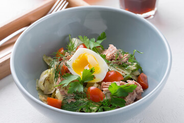 bowl of salad with tuna fish boiled egg and vegetable on white table at cafe