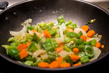 Wok cooking. Professional homemade cuisine, gourmet asian recipe with vegetables (onions, carrots, celery, peppers)