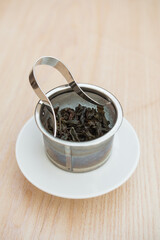 Qilan (Rare orchid) oolong tea leaves in a metal filter. Deliciously sweet and nutty. Beautiful close up of the perfectly shaped wet tea leaves in the metal teapot filter. Vertical.