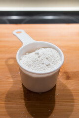 Wheat flour in a measuring cup on a wooden board. Professional food photography. Vertical shot.