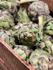 Obraz premium Artichokes for sale in farmers market or supermarket. Market hall. Presented in wooden box. Cynara cardunculus var. scolymus.