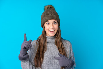 Teenager girl with winter hat over isolated blue background with surprise facial expression