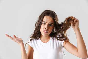 Displeased beautiful girl showing her hair and holding copyspace