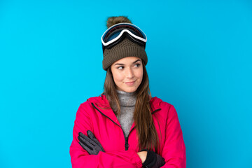 Teenager skier girl with snowboarding glasses over isolated blue background thinking an idea