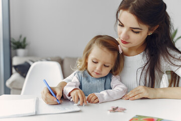 Tutor with pupil. Little girl studying. Private lesson. Mother helps her daughter.