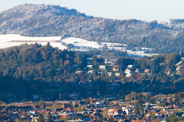 Freiburg im Breisgau/Germany - 11 09 2012: Picturesque view of the city from the mountain, snow-covered Black forest, mountains in the clouds. Early sunny winter morning 