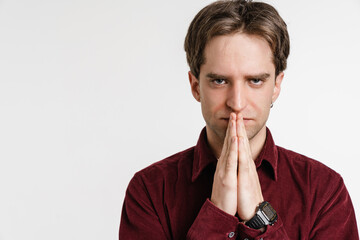 Handsome confident guy looking at camera holding palms together