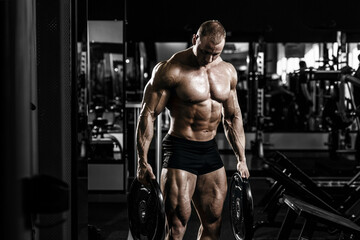 Obraz na płótnie Canvas Muscular athletic bodybuilder fitness model doing exercises in gym.