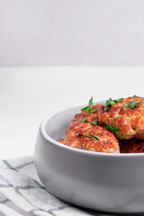 Meat cutlets with mixed mince in the ceramic bowl on the white table. Hot homemade meal. Copy space