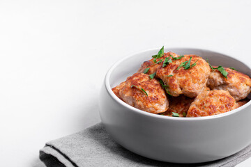 Meat cutlets with mixed mince in the ceramic bowl on the white table. Hot homemade meal. Copy space