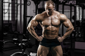 Fototapeta na wymiar Muscular athletic bodybuilder fitness model doing exercises in gym.