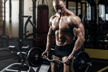 Fototapeta na wymiar Muscular athletic bodybuilder fitness model doing exercises in gym.