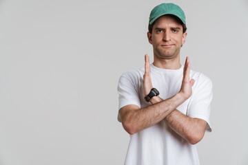 Young displeased man in cap showing stop gesture on camera