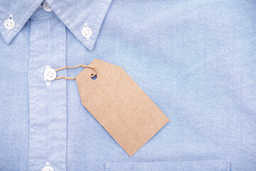 Blank paper label or tag on top of blue shirt, space for text