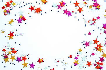 Multicolored stars confetti on white background. Festive confetti. Copy space. Top view. Space for text.