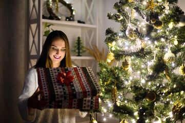 Happy cheerful young surprised woman opening Christmas gift