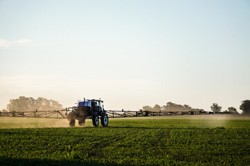 fumigadora, fumigando un campo de soja erde con un abundante cielo y arboles 