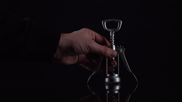Silver colored bottle opener on black background. Universal shiny corkscrew tool with spiral for opening beverage drinks isolated on dark backdrop with space for text