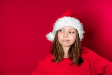 pretty young girl with Santa Claus cap and red pullover in front of red background