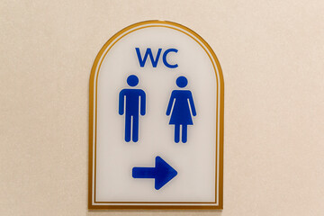 A sign showing the direction of toilets with blue silhouettes.