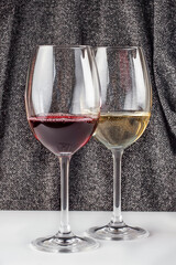 Two glasses of red and white wine on a draped background of shiny fabric