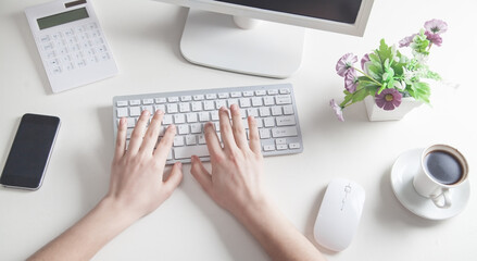 Hands typing on computer keyboard in office desk. - obrazy, fototapety, plakaty
