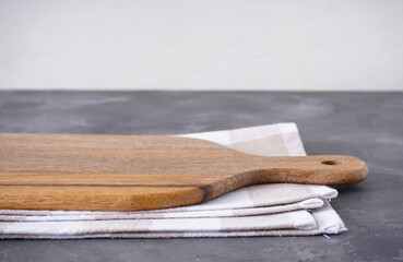 Cutting board with a kitchen towel on a gray background, space for text. Close-up.