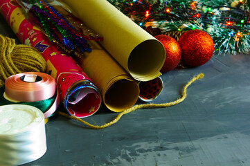 Christmas background with rolls of wrapping paper, ribbons and threads for decorating gifts.