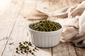 Green soy beans in white bowl on wooden table. 	