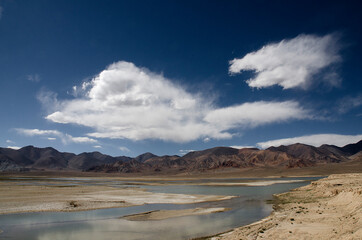 Scenic view of a river into a plateau under big white clouds