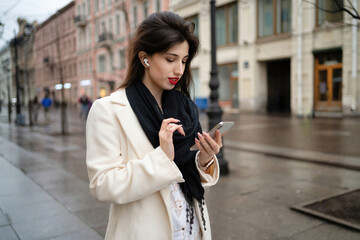 Girl with a phone and headphones on the street. Looking and talking on the phone