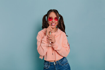 Smiling funny girl with happy emotions enjoying time during photoshoot in studio wearing round oink...