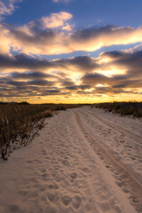 Fototapeta na wymiar Sandy beach road leading to a vibrant golden sunset. Jones Beach New York