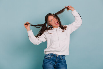 Funny laughting woman playing with her hair making faces and dancing over isolated background
